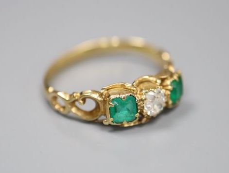 A Victorian style yellow metal (stamped 18ct), two stone emerald and single stone diamond set ring, size L, gross 2.2 grams.